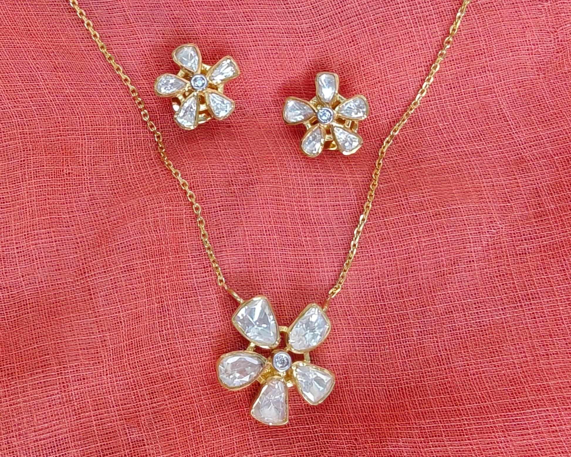 Flower-shaped jewelry set with necklace and earrings on a pink fabric background